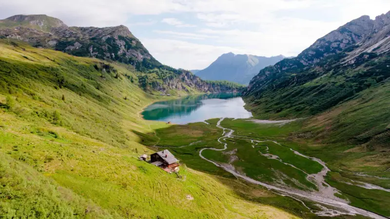 Idyllischer Salzburg See, umgeben von grünen Bergen. Eine Hütte am Hang lädt zum Verweilen ein.