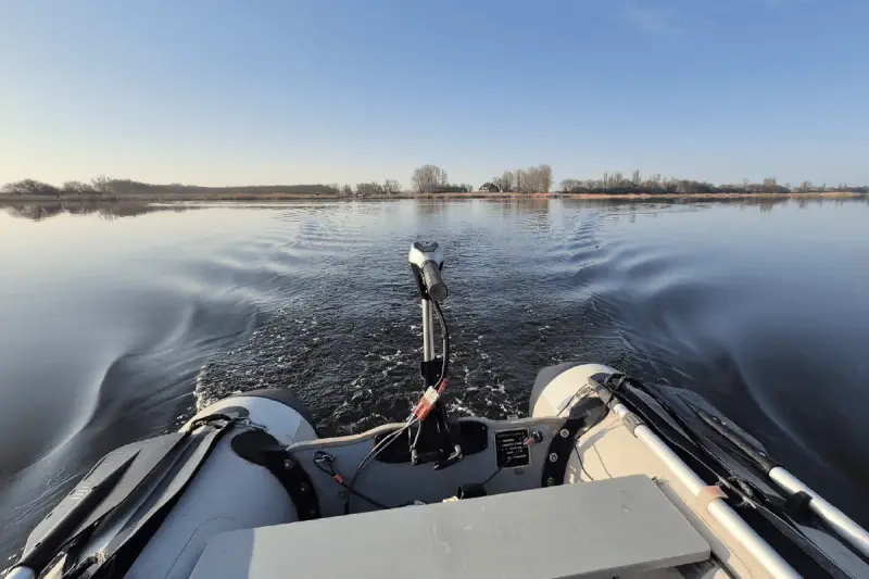 Schlauchboot mit Außenborder auf ruhigem Wasser. Die Beleuchtung des Schlauchboots entspricht der Vorschrift für sicheres Fahren.