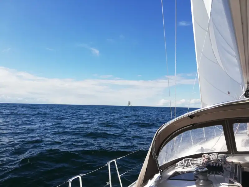 Segeln in Deutschland: Ein Segelboot gleitet über das Meer, im Hintergrund ein weiterer Segler unter blauem Himmel.